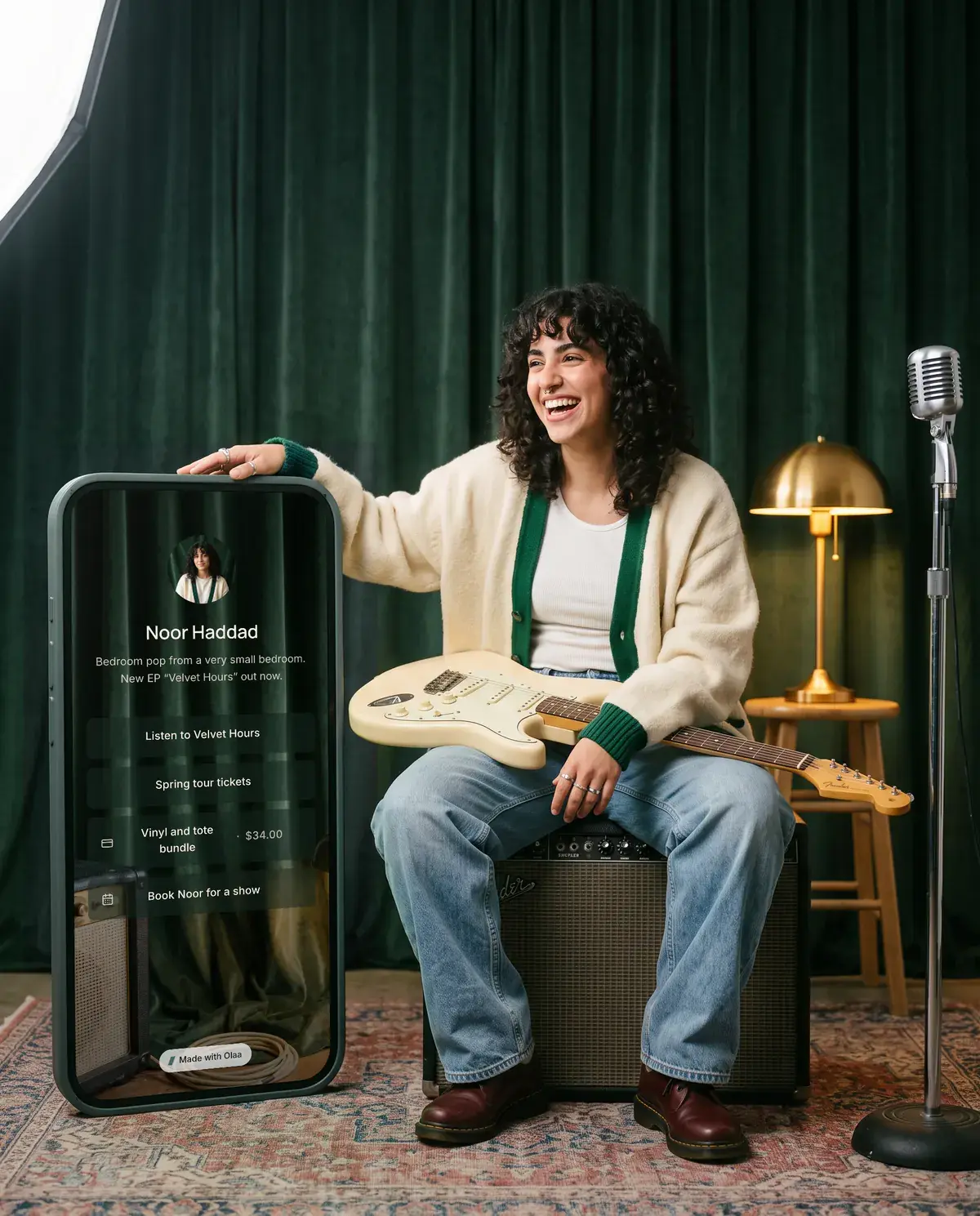Noor Haddad, songwriter. Beside them stands a giant phone showing their Olaa page.