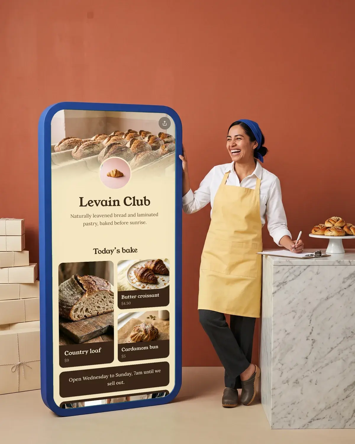 A baker signs for a delivery of pastry boxes beside a giant phone showing the Levain Club page